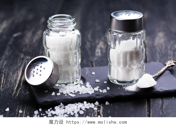 木桌子上放着两瓶海盐海盐粗细玻璃盐瓶